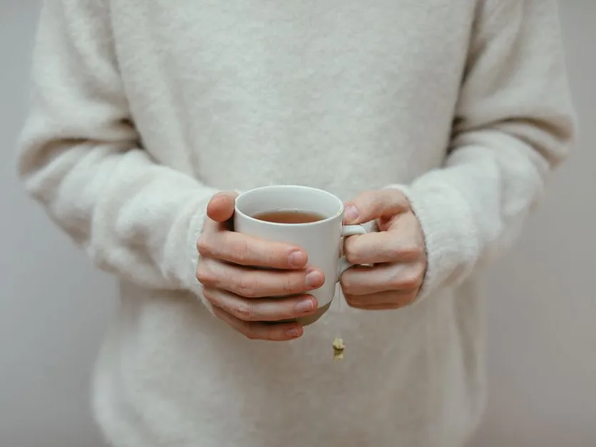 Mains tenant une tasse de tisane chaude, moment calme à la maison